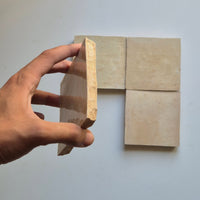 Hand holding a Linen Beige zellige tile showing the hand cut edge and natural terracotta clay body